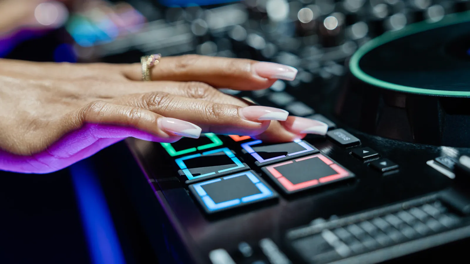 Una mano sobre los pads MPCe de la Denon DJ PRIME 4 G2, iluminados en colores